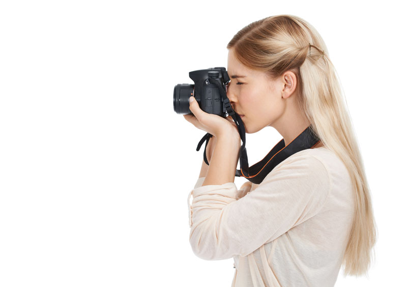 Side view of a woman holding a camera up to her eye, taking a photo.