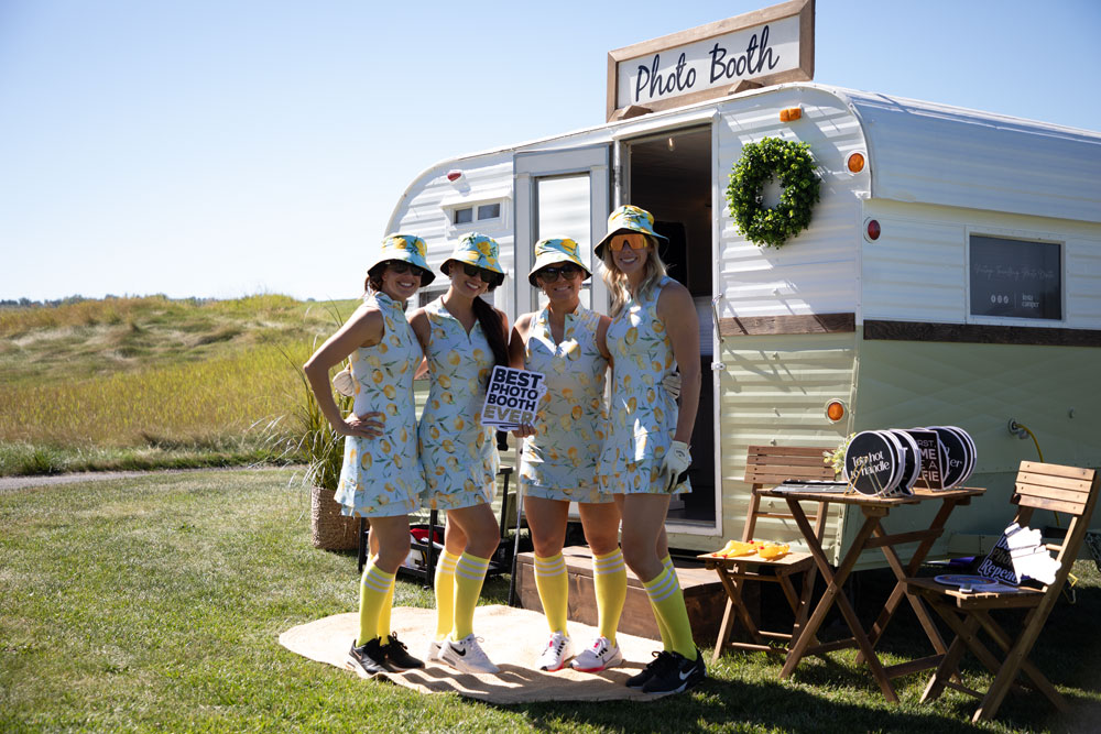 Outdoor photo booth trailer setup with guests posing in matching outfits