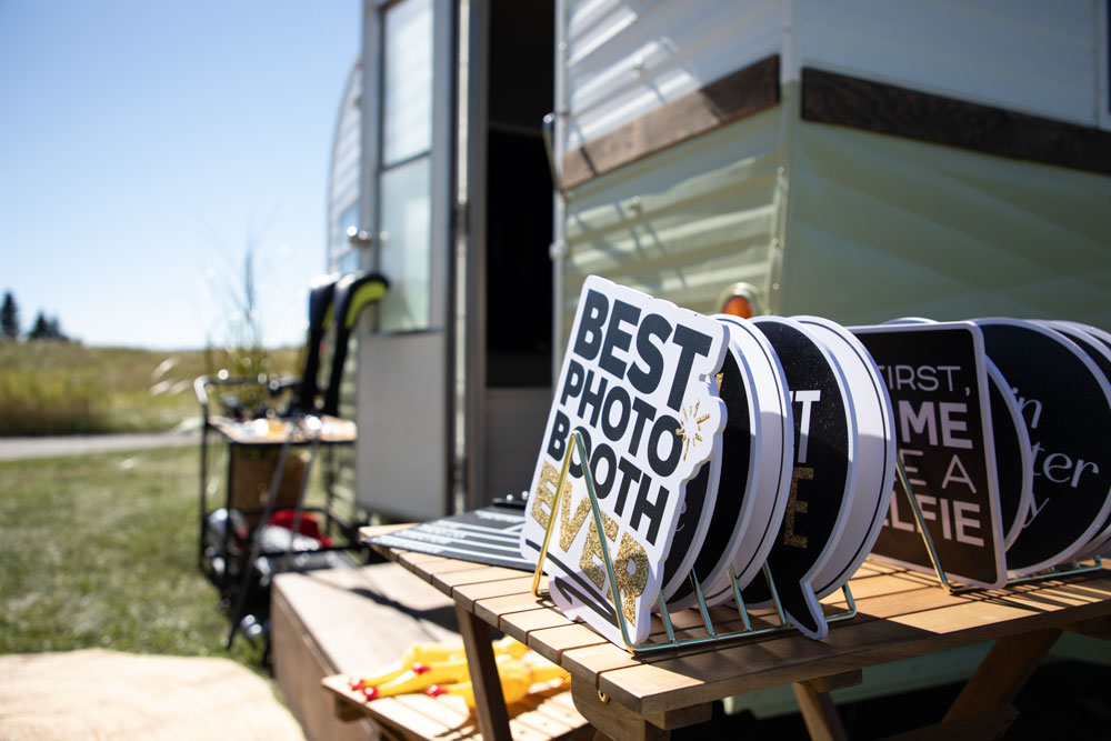 Close-up of photo booth props displayed on a table beside a vintage trailer