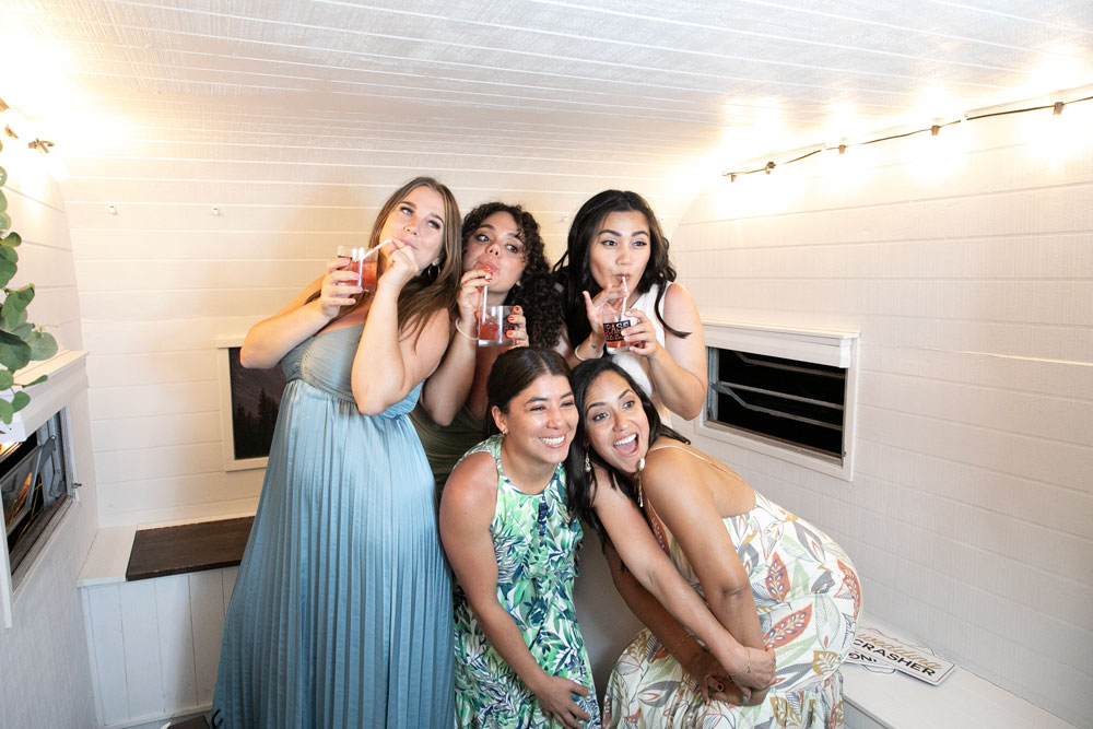 Group of friends laughing and posing inside a photo booth at a celebration