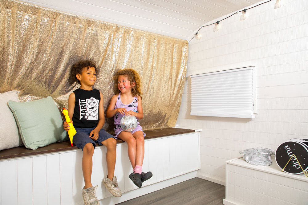 Children smiling inside a photo booth holding fun props during an event