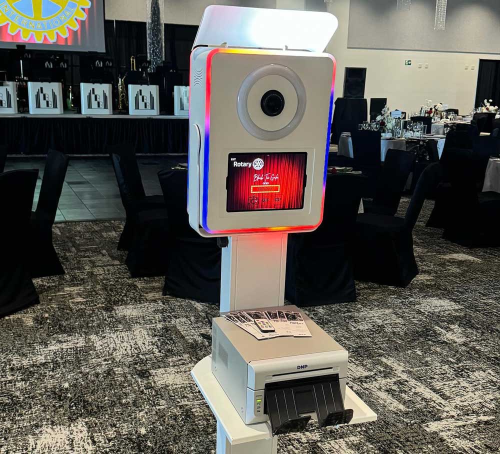 Open-air photo booth with built-in camera and instant printer set up at a formal event